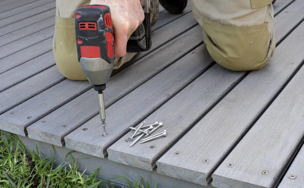 An image of a deck contractor screwing in boards for a new deck.