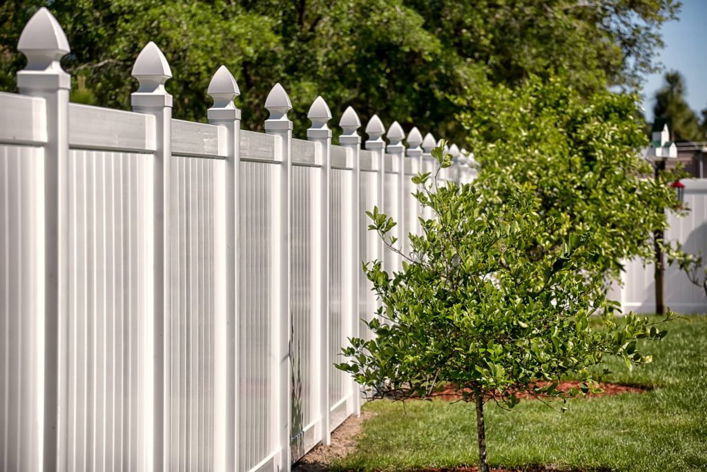 An image of a stylish white fence with pointed posts.